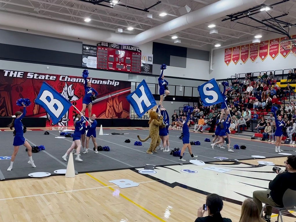Image of a group of cheerleaders doing a routine during a state competition