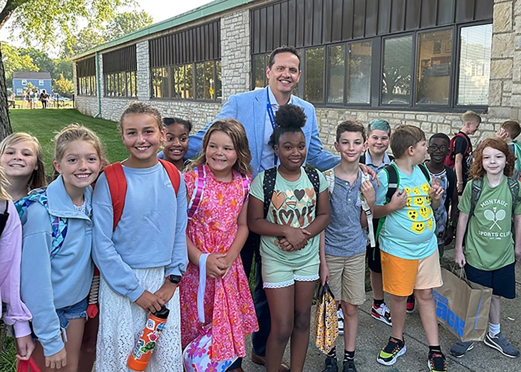 Image of Superintendent Dr. Jason Fine posing with a group of young students outside Maryland Elementary School on the first day of school