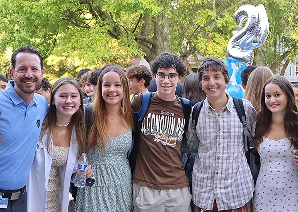 Image of 5 high school students arm in arm along with a male teacher before the first day of school begins