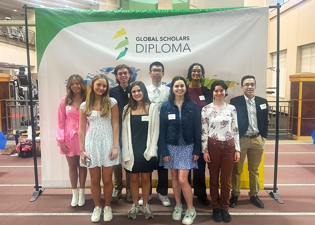 Image of 9 high school students standing together in front of a background that says Global Scholars Diploma